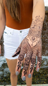 A woman with a jagua henna stain on her arm and hand