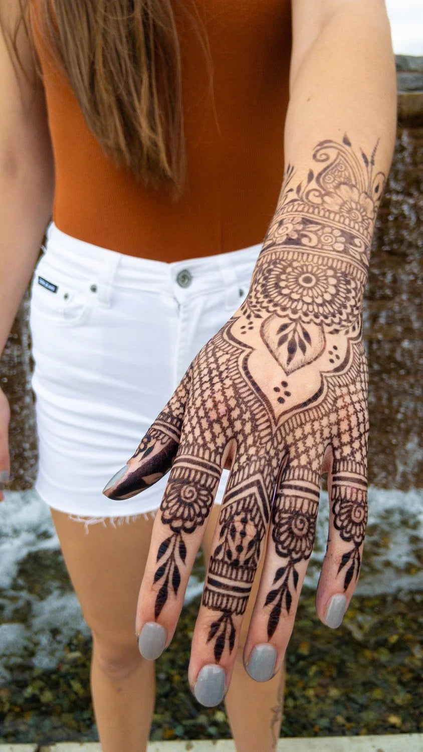 A woman with a jagua henna stain on her arm and hand