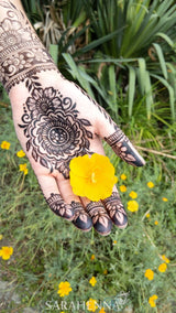 A darkly stained jagua henna design on a woman's palm