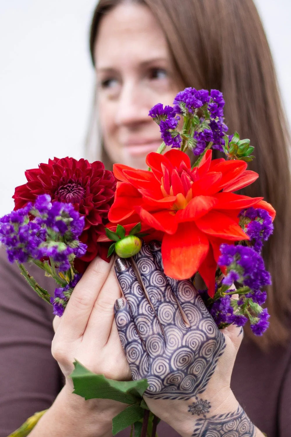 A woman holding flowers with jagua designs on her hands