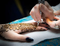 An intricate henna design being applied to a hand
