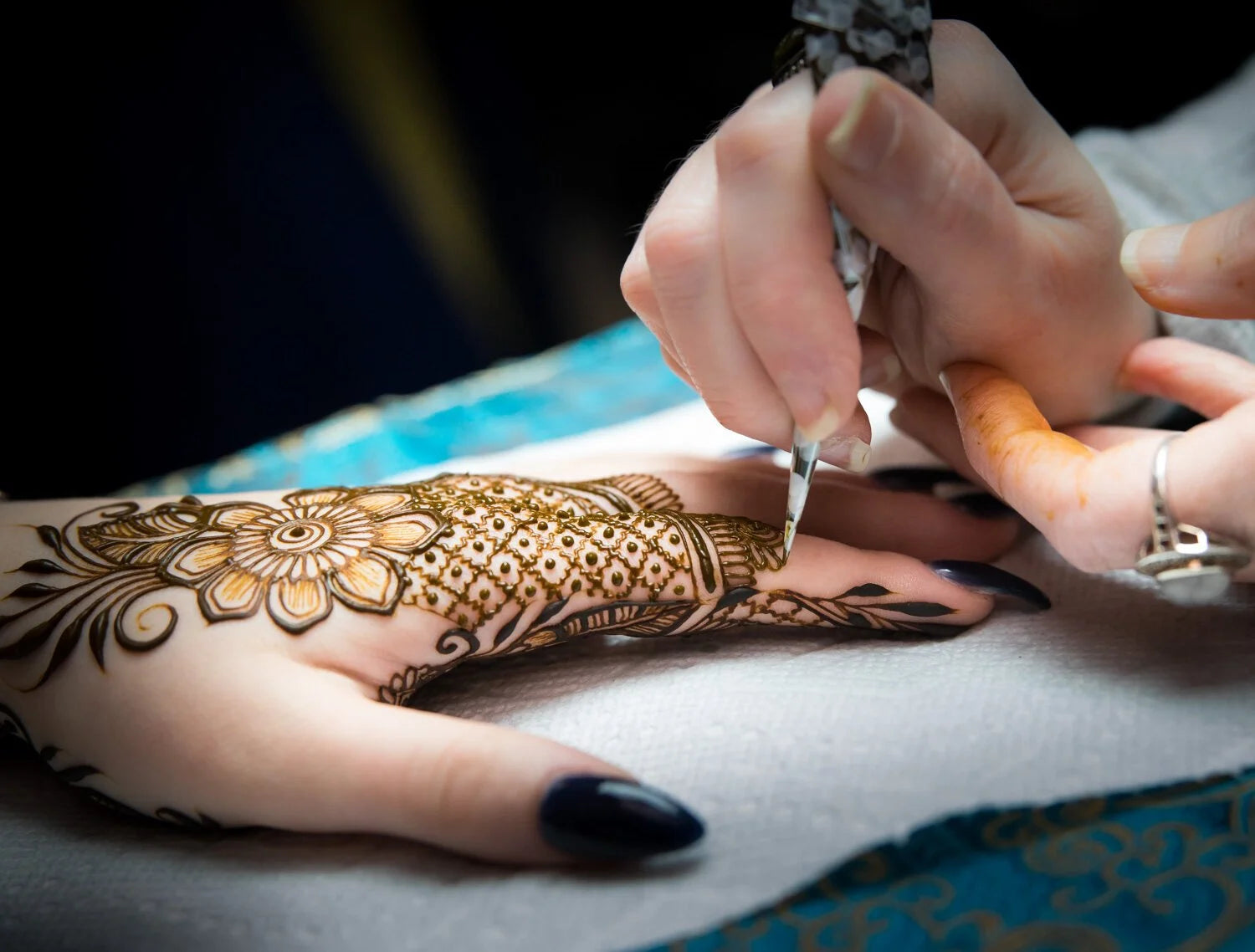 An intricate henna design being applied to a hand