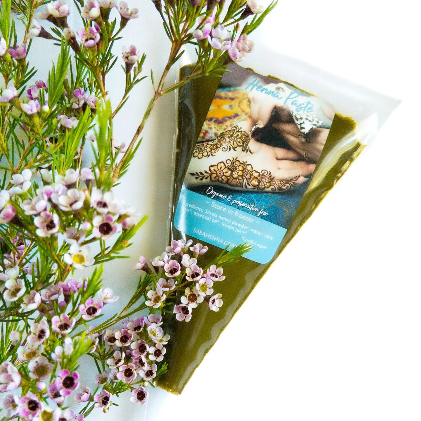 A bulk bag of fresh henna paste next to small purple flowers