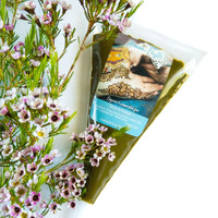 A bulk bag of fresh henna paste next to small purple flowers