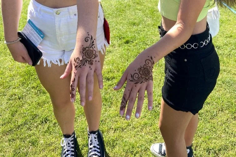 Two teenage girls with simple festival henna designs on their hands