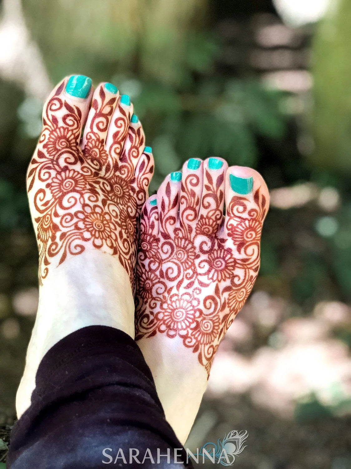 A deep red henna stain in a floral design on feet