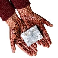 Henna stained hands holding a gift box