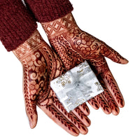 Henna stained hands holding a gift box