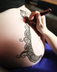 Henna being applied to a pregnant belly