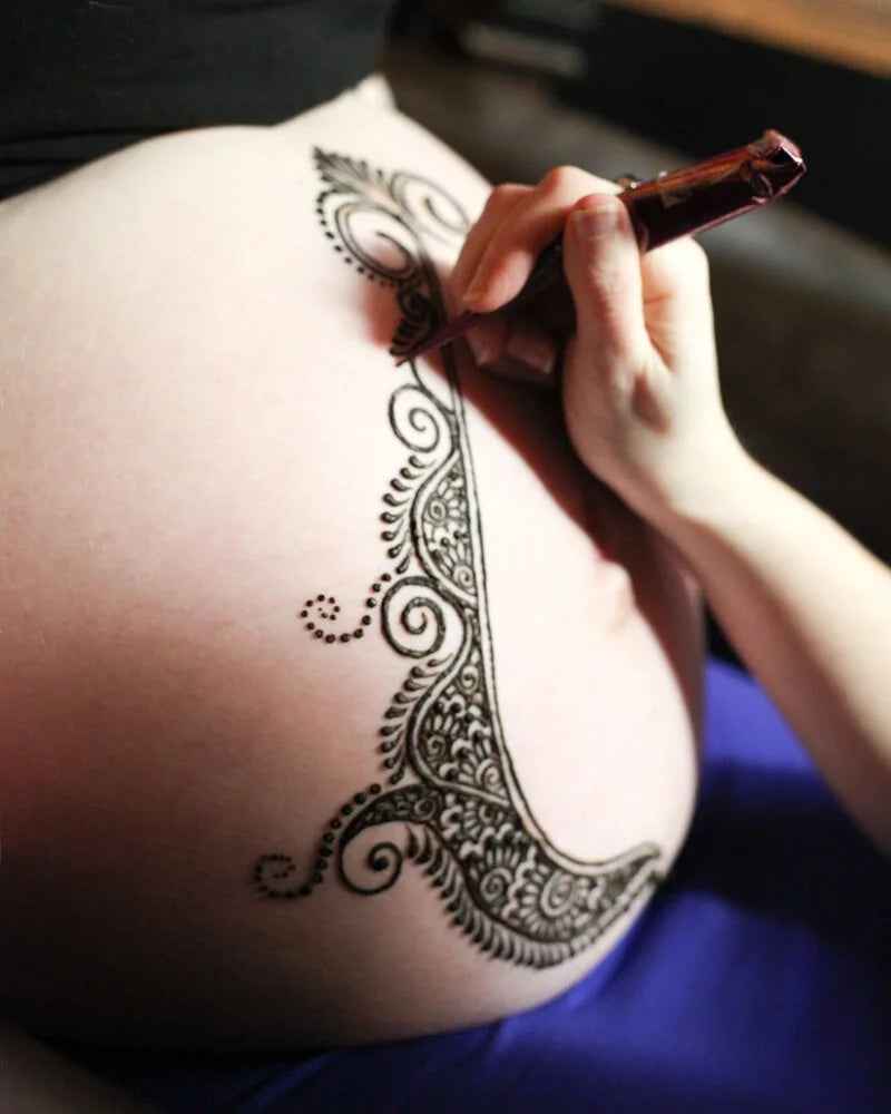 Henna being applied to a pregnant belly