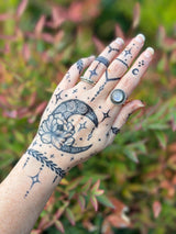 A woman's hand with a celestial moon themed jagua temporary tattoo