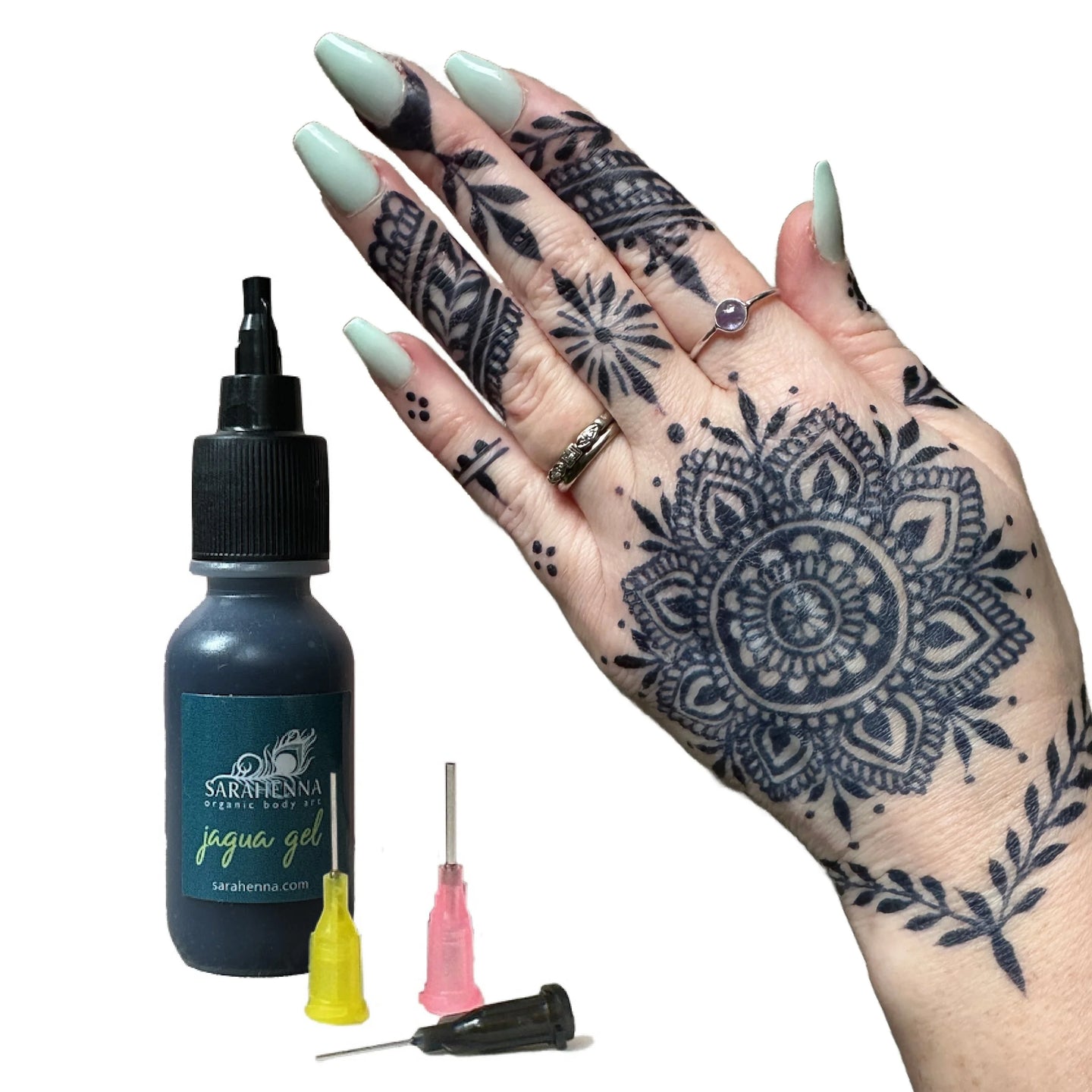 A hand with an intricate, dark jagua stain and a bottle of fresh jagua gel