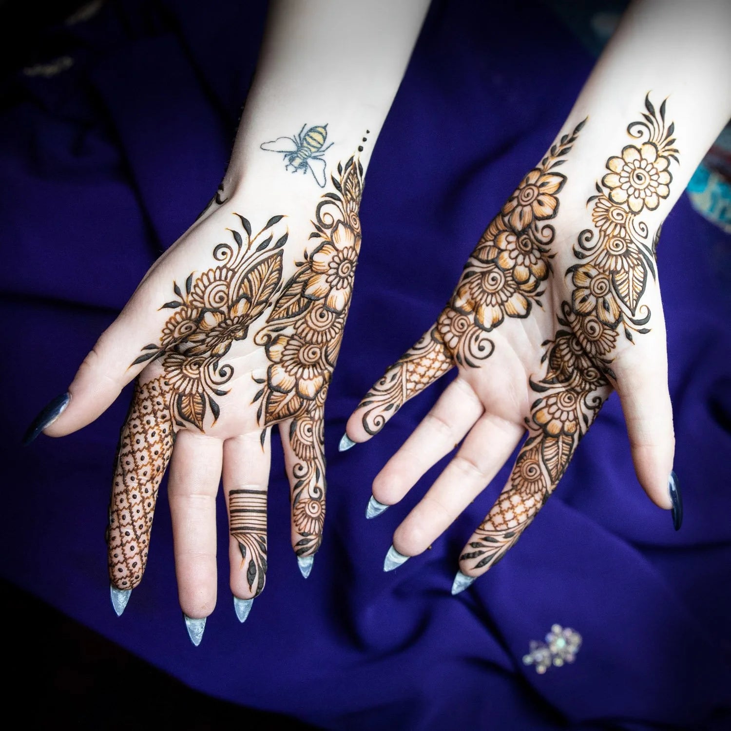 Intricate henna design on the palms of hands that have been sprayed with finishing spray