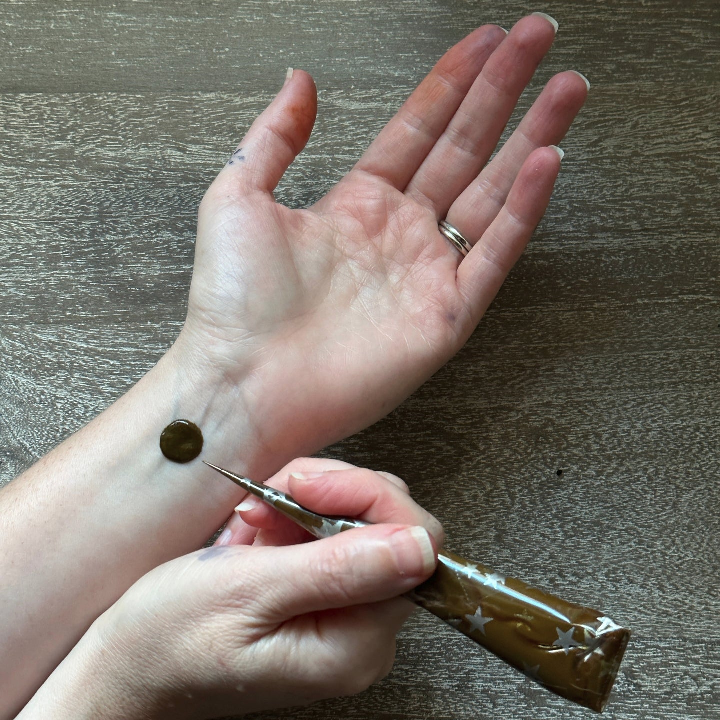 Person applying a small amount of henna to their wrist with a henna cone.