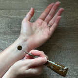 Person applying a small amount of henna to their wrist with a henna cone.