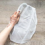 A mesh bag used for straining freshly mixed henna paste, with a henna stained hand next to it