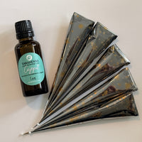 A bottle of essential oil next to fresh henna cones 