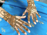 Two hands with intricate henna designs over a blue fabric
