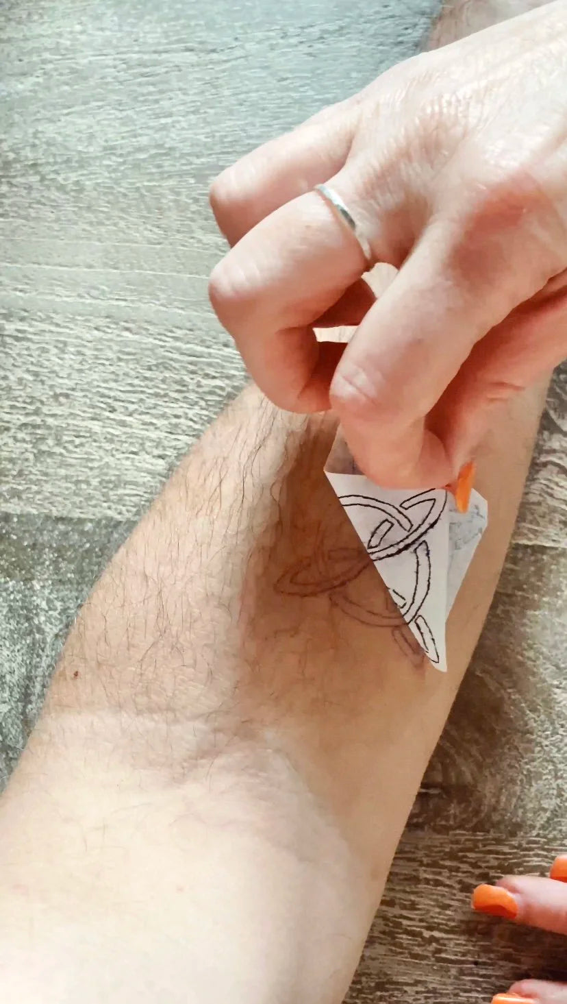 Stencil paper being used to apply a complex design on skin